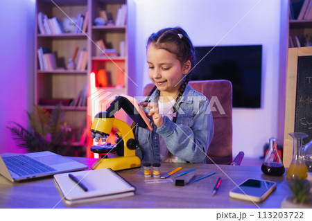 Caucasian child in casual wear studies by doing science in the evening at home. 113203722