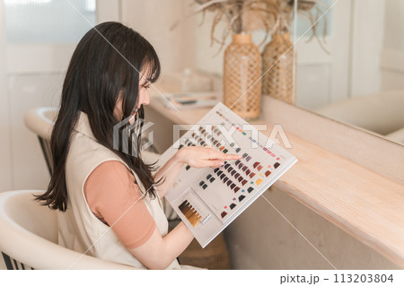 美容室・ヘアサロンでヘアカラーサンプルを見る女性 113203804