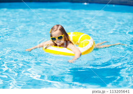Child in swimming pool on ring toy. Kids swim. 113205641