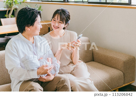 赤ちゃんとスマホアプリを使う若い夫婦・親子・家族・ファミリー 113206842