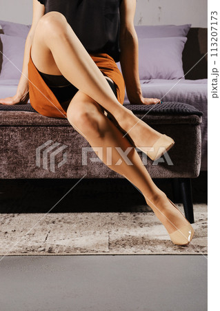 Unrecognizable woman in stockings with garter belt on ottoman Unrecognizable woman in stockings with garter belt on ottoman 113207173