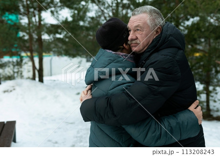 Cute retired couple walking in the park and hugging each other in winter park 113208243