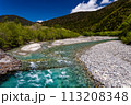 Fast flowing clear river running through a forest and mountains 113208348