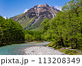 Fast flowing clear river running through a forest and mountains 113208349