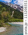 Fast flowing clear river running through a forest and mountains 113208351