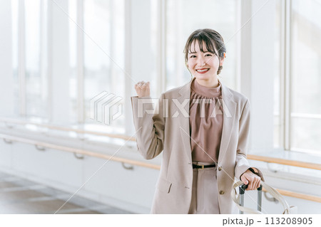 駅・ターミナル・空港のロビーでガッツポーズする女性（出張・旅行・転勤・異動・引っ越し） 113208905