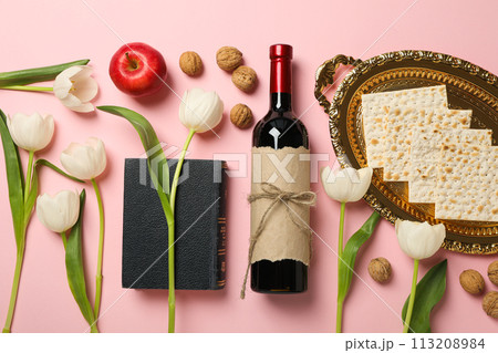 Matzo, bottle of wine, flowers and Torah on pink background, top view 113208984