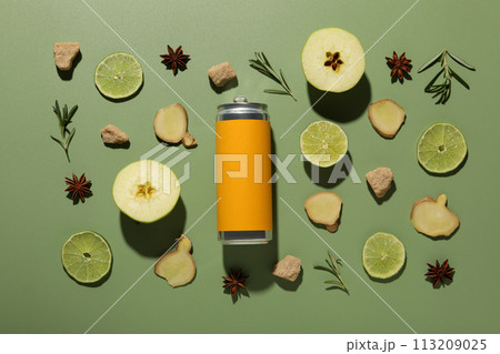 Ginger root, apples and lime pieces and tin can on green background, top view Ginger root, apples and lime pieces and tin can on green background, top view 113209025