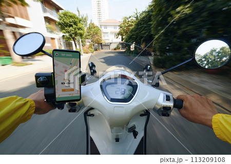 POV of motorbike taxi driver riding fast and checking requests on smartphone 113209108