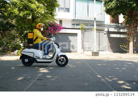 Delivery man with big bag riding motorbike, side view Delivery man with big bag riding motorbike, side view 113209114
