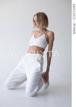 Beautiful blonde girl in a white top and tights posing on a white background 113211495