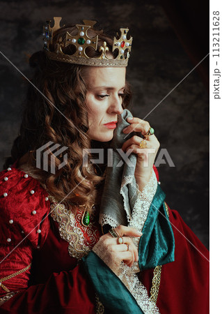 sad medieval queen in red dress with handkerchief crying 113211628