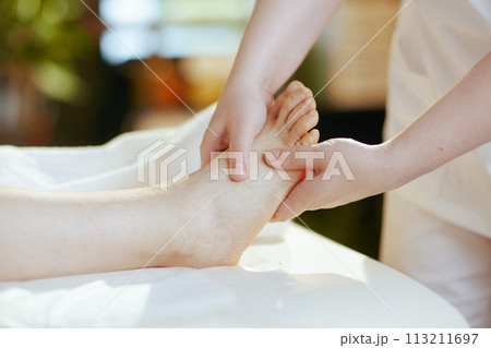 Closeup on medical massage therapist massaging clients foot Closeup on medical massage therapist massaging clients foot 113211697