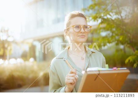 pensive modern business woman in green blouse and eyeglasses pensive modern business woman in green blouse and eyeglasses 113211893