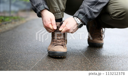 Male hand tie shoelaces on brown shoes closeup Male hand tie shoelaces on brown shoes closeup 113212378