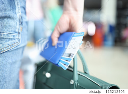 Man holding green briefcase and passport with plane tickets closeup Man holding green briefcase and passport with plane tickets closeup 113212503