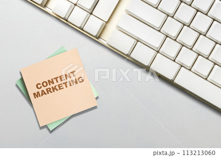 Keyboard and stack of notepaper with content marketing text 113213060