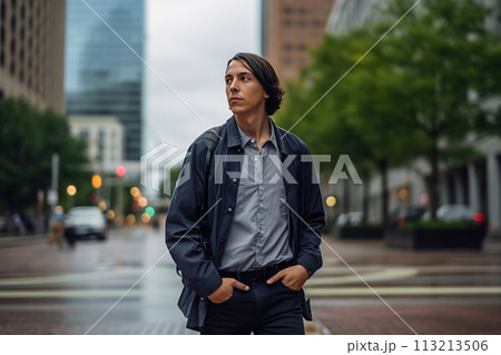 A man wearing a blue jacket and gray shirt is walking down a city street 113213506