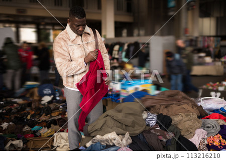 Man African looking at used clothes at a flea market 113216210