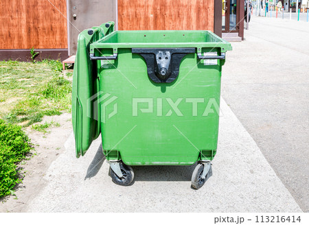 Opened green plastic garbage container at the sunny city street 113216414