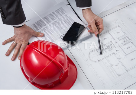 Above view of architect hands revising a house project Above view of architect hands revising a house project 113217792