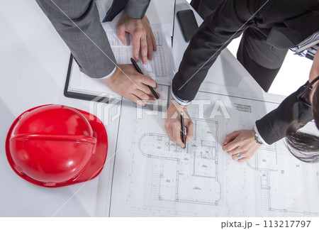 Above view of architects hands revising a house project Above view of architects hands revising a house project 113217797