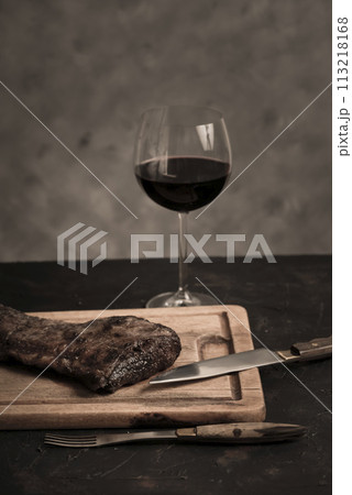 Roasted beef ribs with a glass of red wine presented on the table, traditional Argentine cuisine, Asado barbecue, Patagonia, Argentina. 113218168