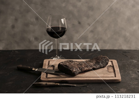 Roasted beef ribs with a glass of red wine presented on the table, traditional Argentine cuisine, Asado barbecue, Patagonia, Argentina. 113218231