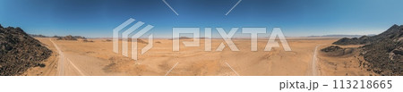 Panoramic drone picture of a lonely gravel road through the desert 113218665