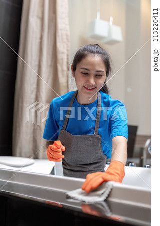 Professional cleaning service company employee in rubber gloves cleaning and detergent spray in bathroom 113220411