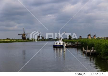 Kinderdijk, South Holland, Netherlands - July, 2, 2023: Beautiful wooden windmills at sunset in the Dutch village of Kinderdijk. Windmills run on the wind. The beautiful Dutch canals 113221140