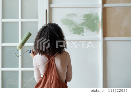 Woman with paintroller looking at wall Woman with paintroller looking at wall 113222925