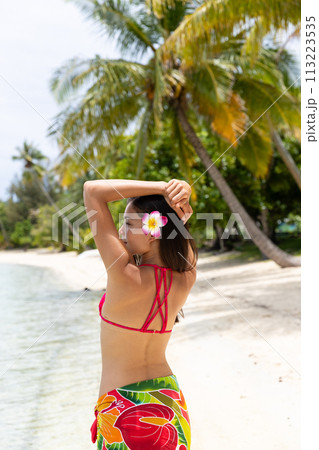 Vacation Luxury Travel woman on Tahiti paradise beach. Girl in Bikini, traditional Polynesia pareo with Hawaii hibiscus flower. Image is unretouched and model is without makeup. Real people. Raw Image Vacation Luxury Travel woman on Tahiti paradise beach. Girl in Bikini, traditional Polynesia pareo with Hawaii hibiscus flower. Image is unretouched and model is without makeup. Real people. Raw Image 113223535
