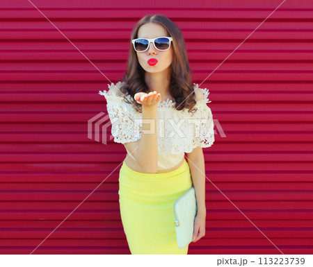 Beautiful young woman model blowing kiss posing on pink background 113223739