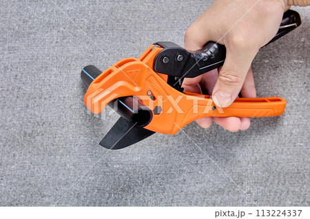 Pipe scissors cutter hand plumbing tool for cutting HDPE pipes, close-up on gray background. Pipe scissors cutter hand plumbing tool for cutting HDPE pipes, close-up on gray background. 113224337