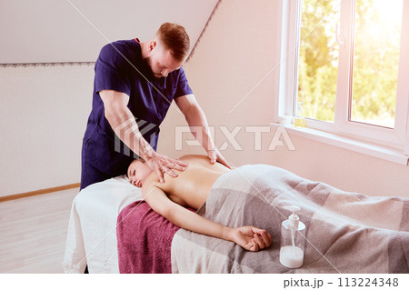 Young masseur brought massage table to home woman in her 20s to give her back massage. Young masseur brought massage table to home woman in her 20s to give her back massage. 113224348