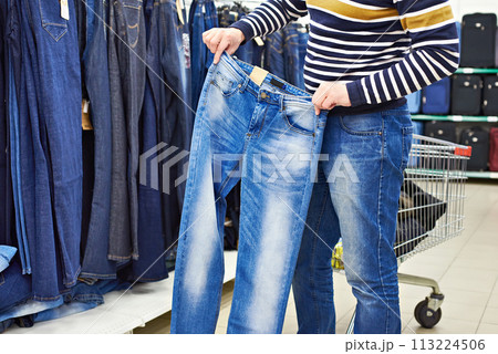 Man chooses blue jeans in shop 113224506