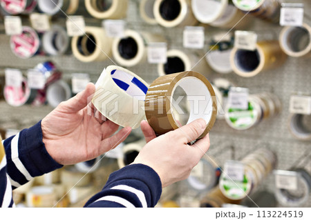 Man buyer chooses adhesive duct tape in store Man buyer chooses adhesive duct tape in store 113224519