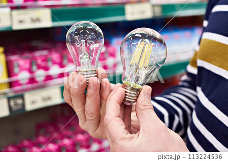 LED and incandescent lamp in hands on store LED and incandescent lamp in hands on store 113224536