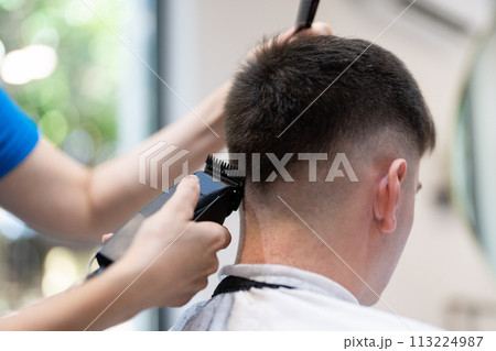 Professional hairdresser working with client. Hair salon master trimmed client hair with electric razor at barber shop. Professional hairdresser working with client. Hair salon master trimmed client hair with electric razor at barber shop. 113224987