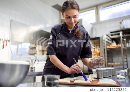 Female baker in uniform preparing croissants in kitchen 113225253