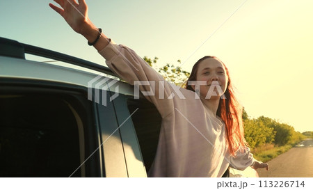 Overjoyed laughing woman with raising hands riding in car window road trip adventure summer vacation. Happy female tourist flying driving automobile travel journey enjoy freedom air positive emotion 113226714