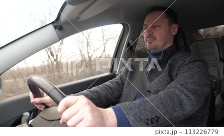 Handsome casual modern man driving car hands holding steering wheel closeup. Bearded confident pensive male driver riding automobile speed traffic transportation at autumn countryside highway 113226779