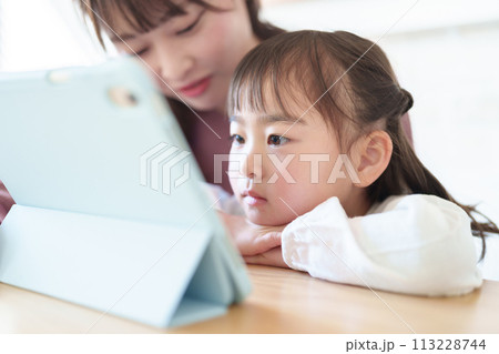 リビングでタブレットを使う女の子とお母さん 113228744