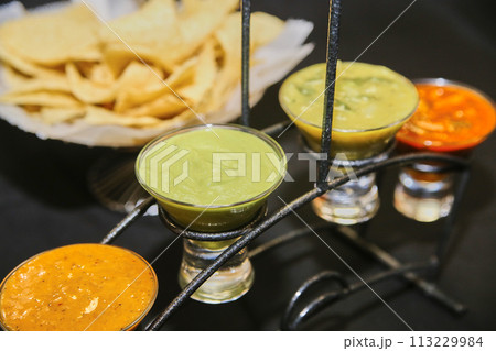 Trio of Mexican Salsas with Tortilla Chips on Wrought Iron Stand 113229984