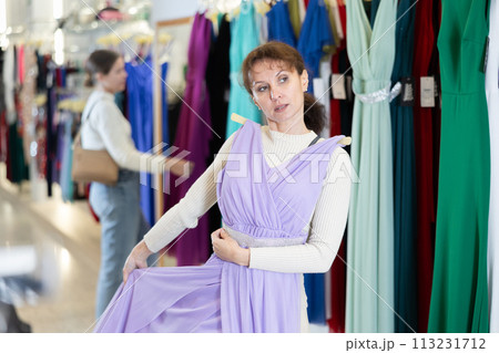 Adult woman choosing dress in store Adult woman choosing dress in store 113231712