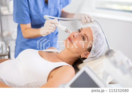 Young woman cosmetologist doing cleansing procedure to young woman Young woman cosmetologist doing cleansing procedure to young woman 113232080