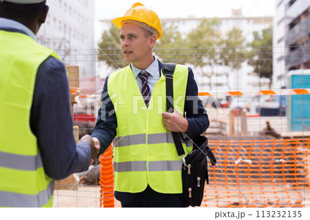 Successful architect and engineer shake hands on construction site 113232135