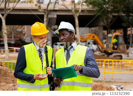 Two men workers discuss the project, holding work documents 113232390