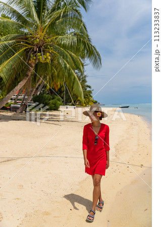 Travel woman walking on beach smiling in sundress and sunhat on Matira Beach, Bora Bora, Tahiti, French Polynesia. Image is unretouched and model is without makeup. Real people. Raw Image 113233837